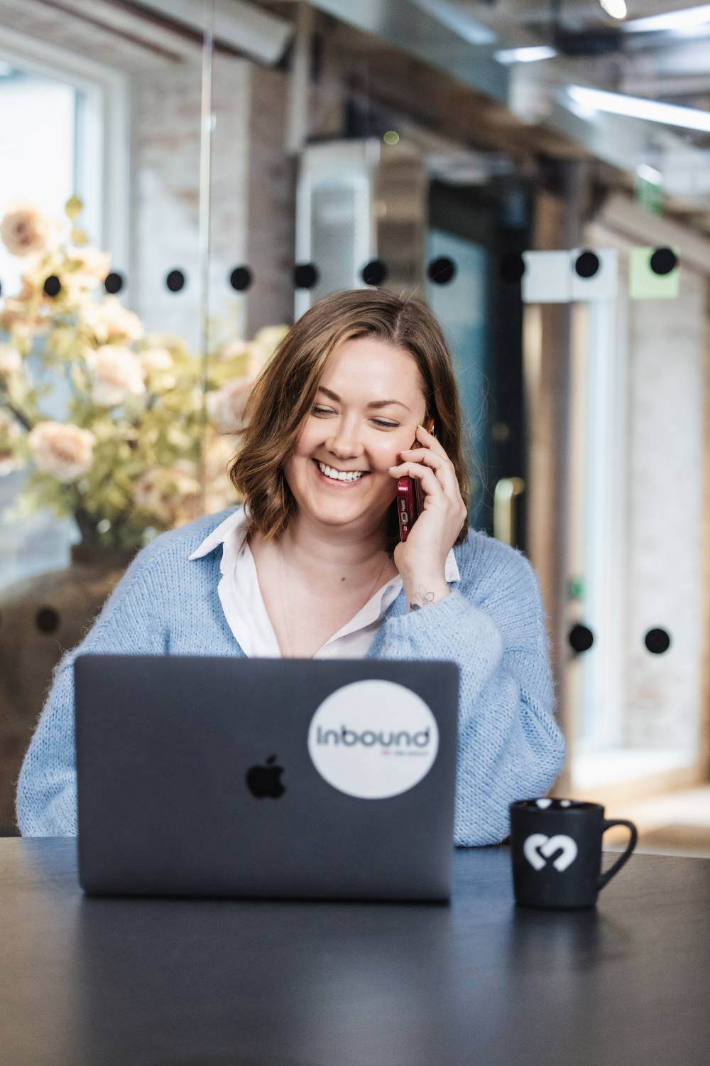 Smilende medarbeider hos Inbound snakker i telefonen, klar til å hjelpe B2B-kunder med markedsføringsstrategier.