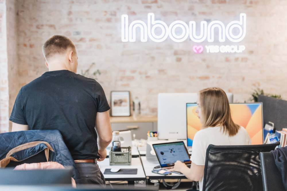 To kolleger på kontoret hos Inbound diskuterer ideer for markedsføringstjenester for små og mellomstore bedrifter.”